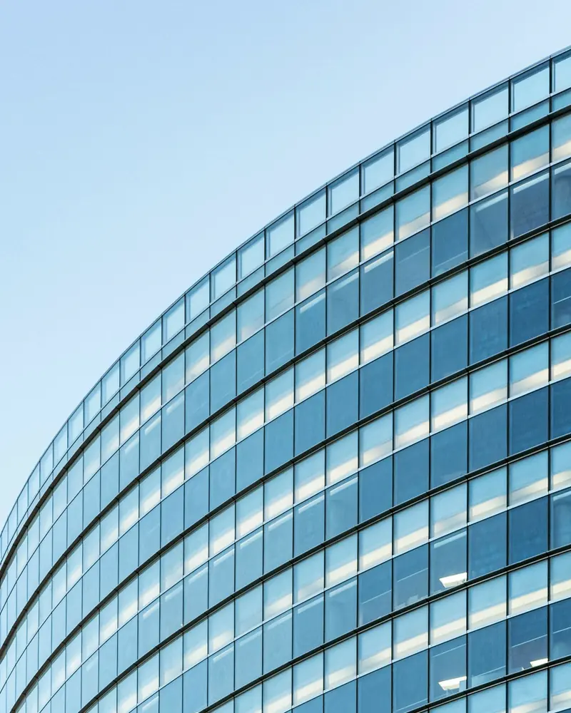 Geschwungene Glasfassade eines Bürogebäudes vor blauem Himmel