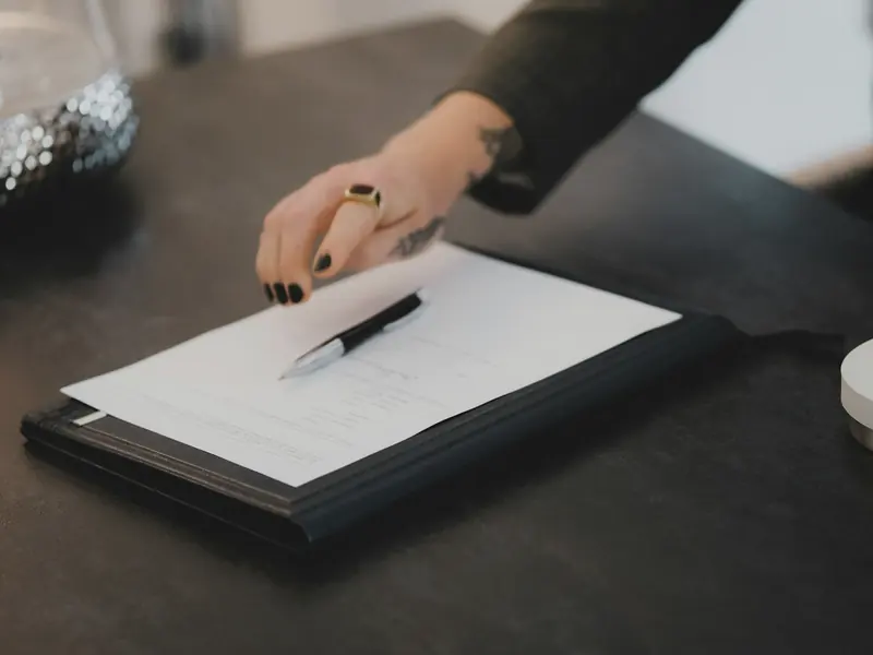 Hand signing a document on a clipboard